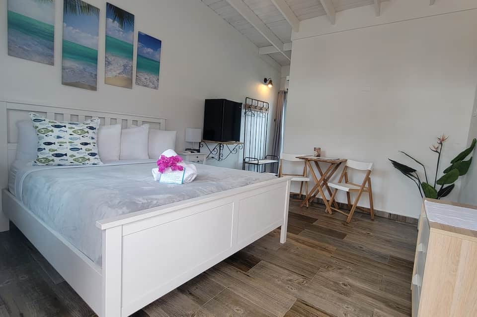 Bright beach-themed hotel room with white bed and ocean artwork on walls