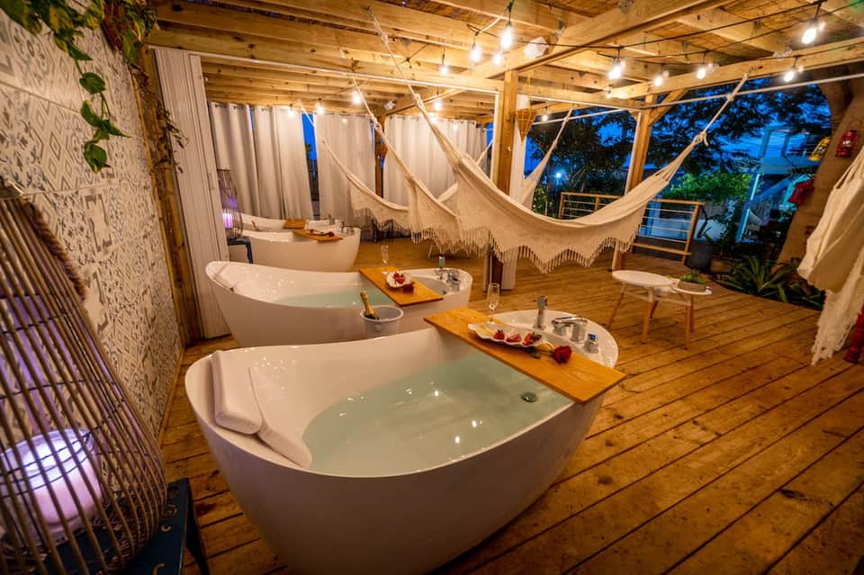 Spa relaxation area with multiple white soaking tubs and hanging hammocks