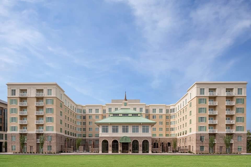 Modern resort building with cream and tan facade, manicured lawn, and central courtyard