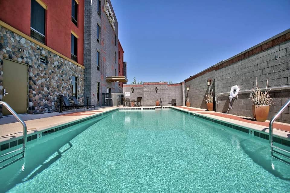 Indoor heated pool with turquoise water in courtyard surrounded by brick buildings