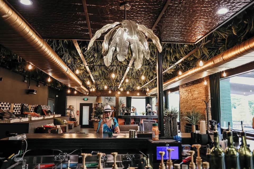 Trendy coffee shop interior with exposed brick, hanging botanical décor, and copper piping