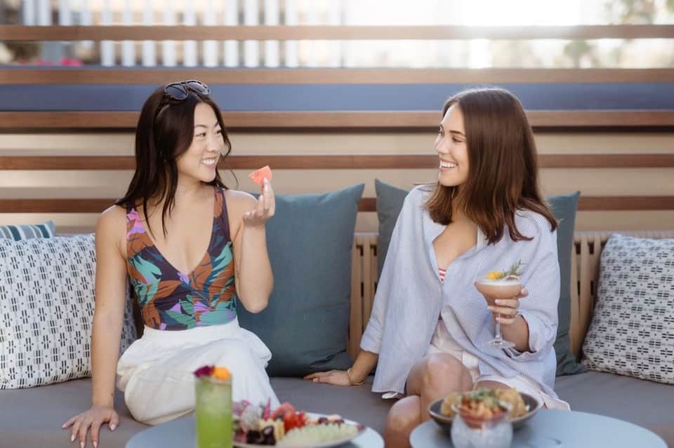 Two women enjoying drinks and appetizers at casual lounge seating area