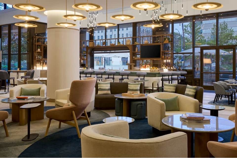 Upscale hotel lobby lounge with warm lighting, modern furniture, and floor-to-ceiling windows