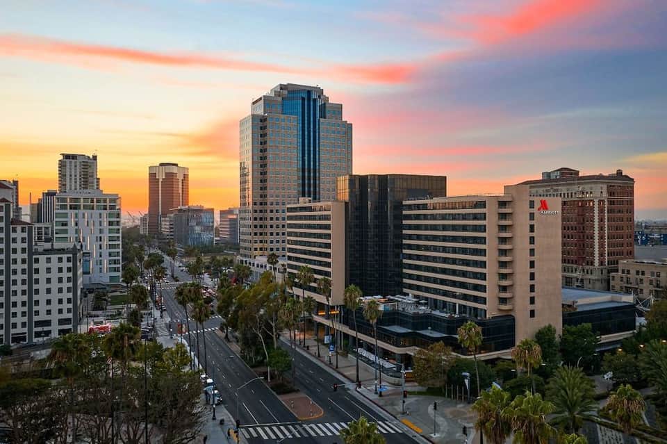 Downtown cityscape at sunset with modern high-rise buildings, palm trees, and streets