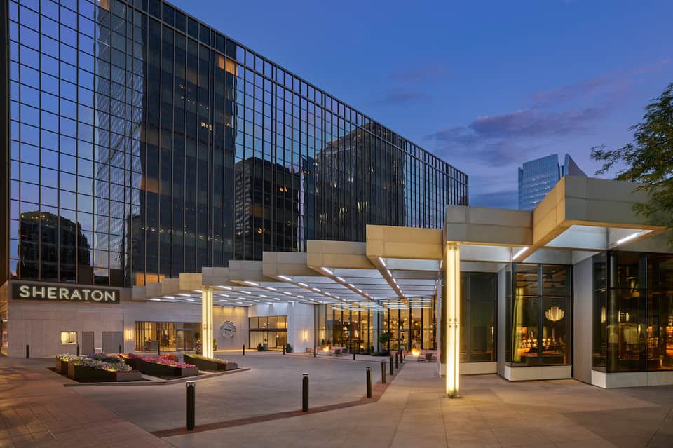 Modern Sheraton hotel entrance at dusk with illuminated architectural canopy design