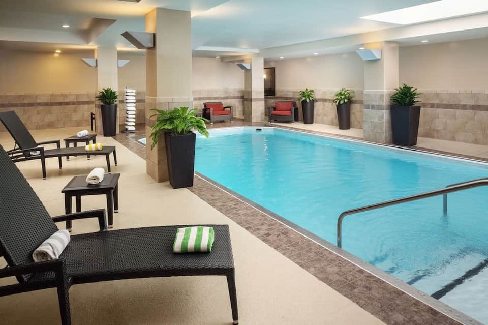 Indoor swimming pool with loungers, potted plants, and lounge seating area in spa facility