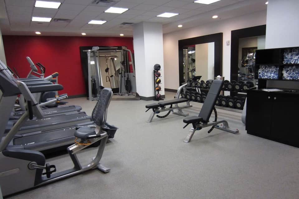 Fitness center with red accent wall, exercise equipment, dumbbells, and workout machines