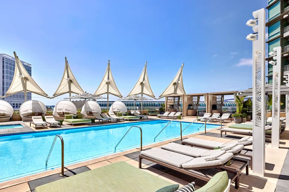 Rooftop pool with white sail-shaped umbrellas and city skyline in background