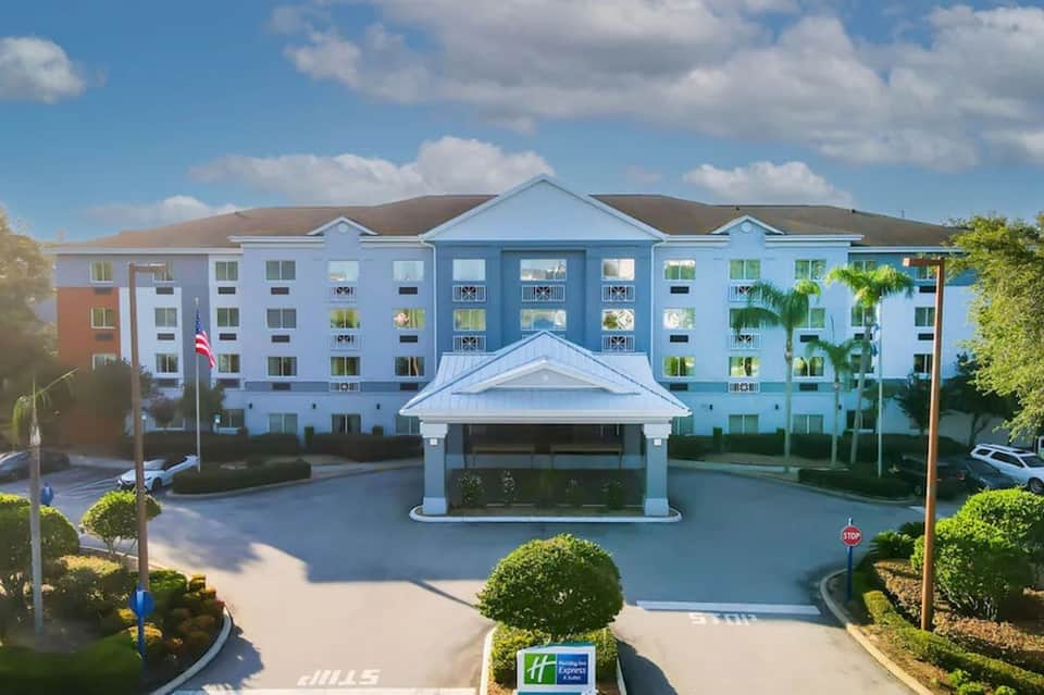 Blue and white multi-story hotel building with covered entrance and manicured grounds