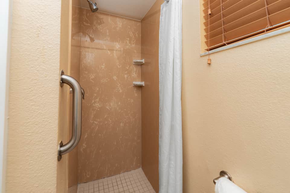 Clean bathroom with walk-in shower, grab bars, and neutral tile and wall finishes