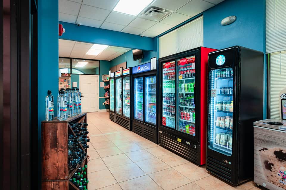 Convenience store interior with turquoise walls and multiple refrigerated beverage vending machines