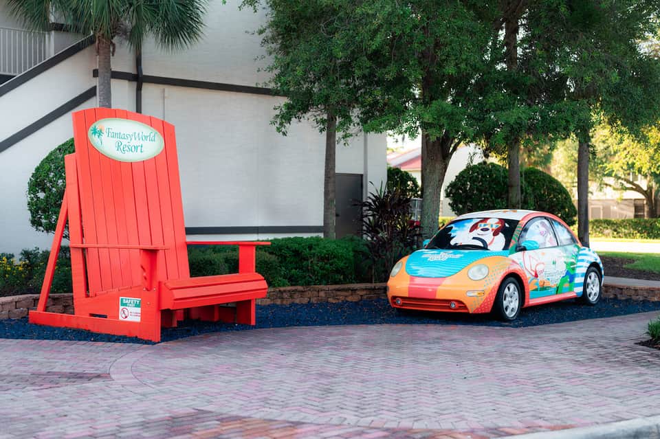 Giant red Adirondack chair and colorful toy car outside FantasyWorld Resort entrance