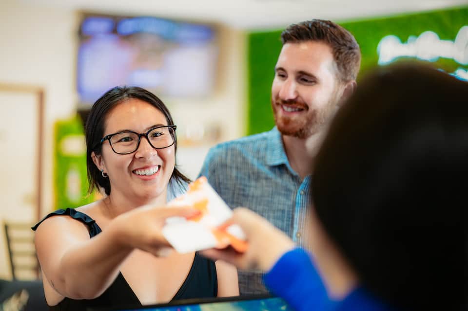Hotel staff member smiling while handing key card to guest at front desk