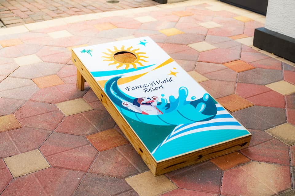 Colorful cornhole game with beach and sun design on brick patio at Fantasy World Resort