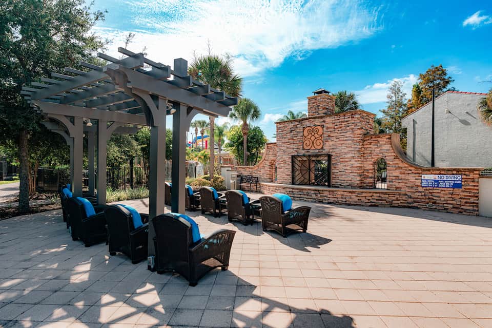 Outdoor lounge area with black and blue chairs under pergola near resort pool