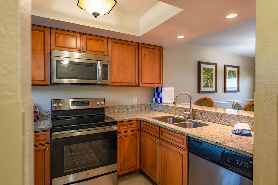 Kitchen with wood cabinetry, granite countertop, stainless steel appliances, and skylight