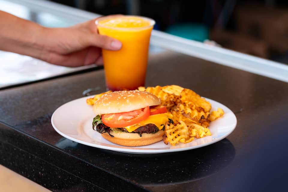 Cheeseburger with waffle fries and orange juice on a black hotel dining table
