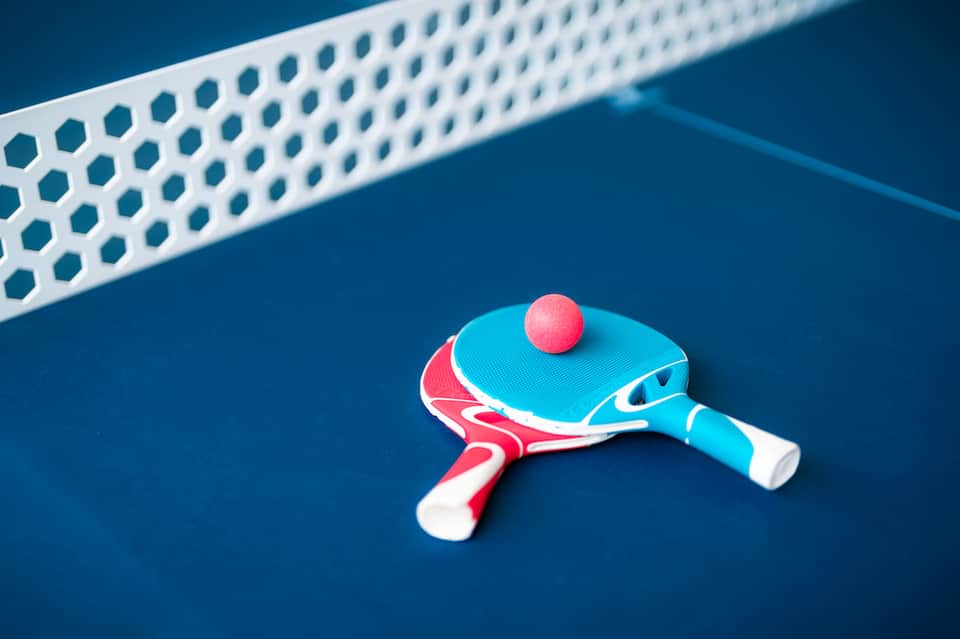 Colorful ping pong paddle and ball on blue table with net