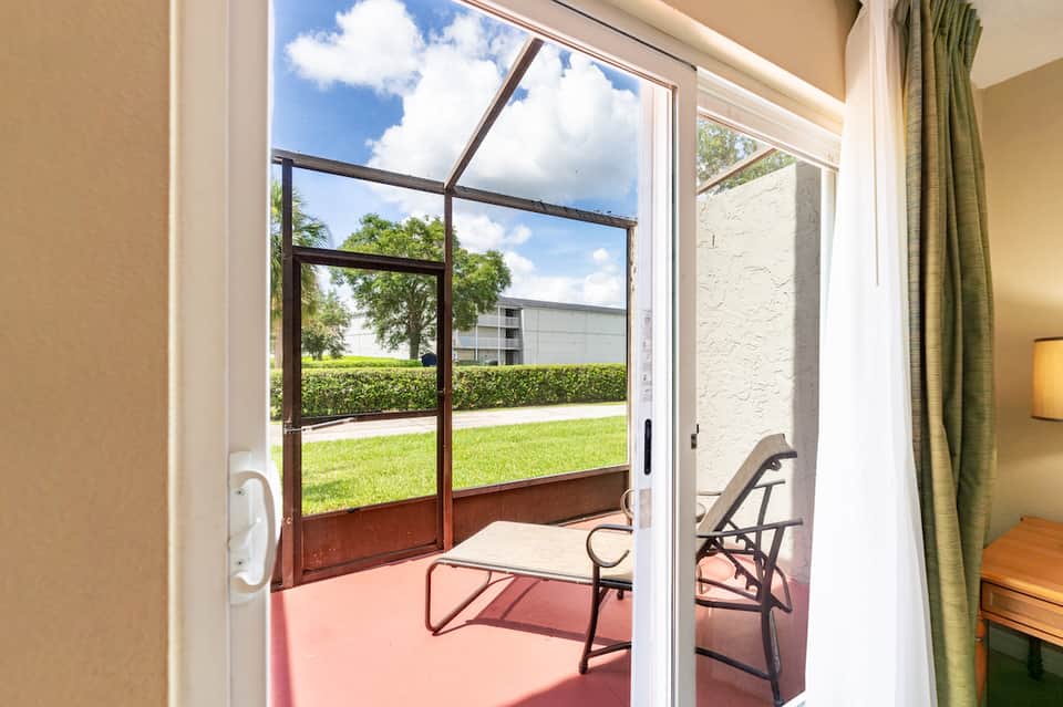 Screened lanai patio with lounge chairs overlooking manicured lawn and landscaping