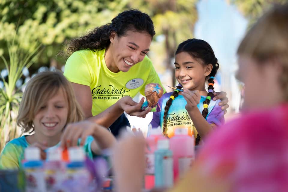 Kids camp counselor and children in neon t-shirts enjoying outdoor activity with leis