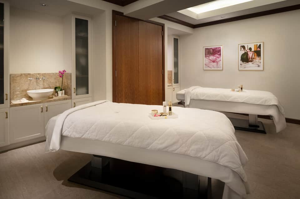 Spa treatment room with two massage beds, sink vanity, and modern neutral décor