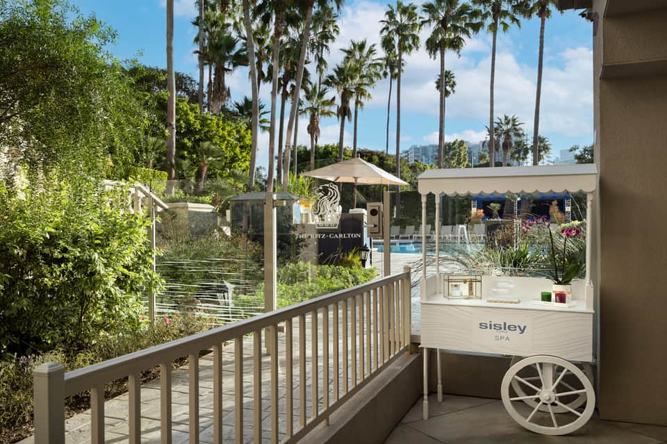Spa entrance with Sisley branding, palm trees, pool area, and landscaped outdoor terrace visible