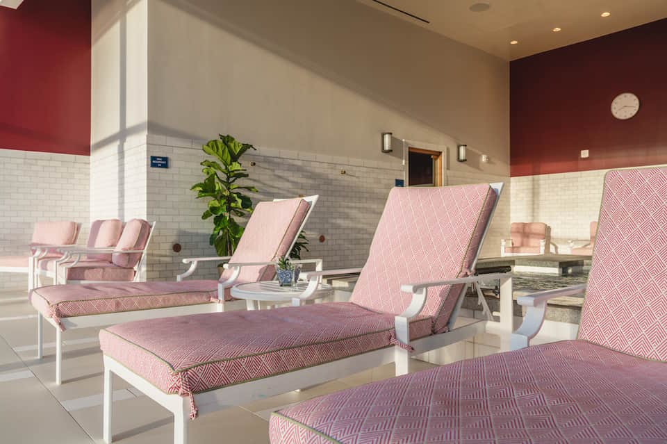 Pink and white lounge chairs arranged in a spa relaxation room with tiled walls