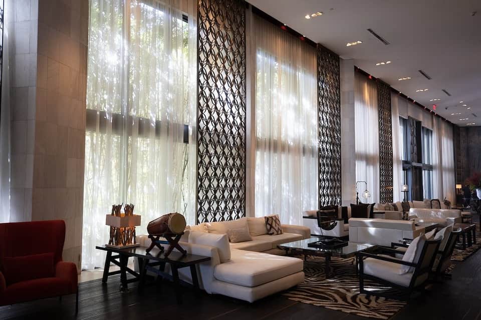 Modern hotel lobby with soaring windows, geometric screens, and contemporary seating arrangements