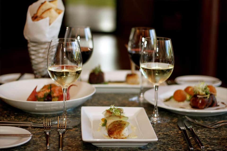 Fine dining table set with white wine glasses and gourmet plated dishes