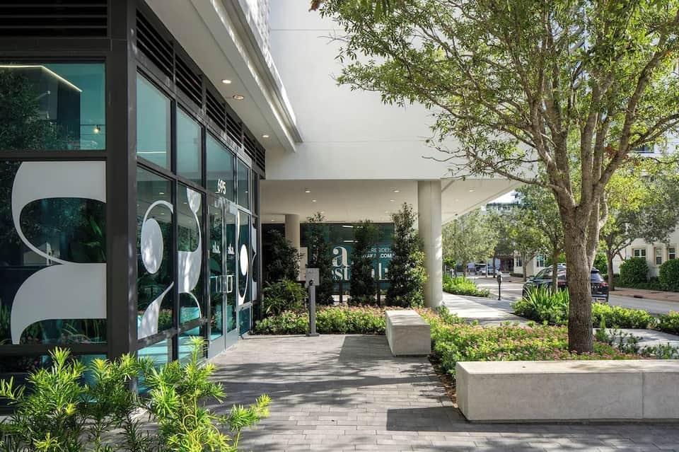 Modern storefront entrance with dark glass doors, contemporary signage, and landscaped planters