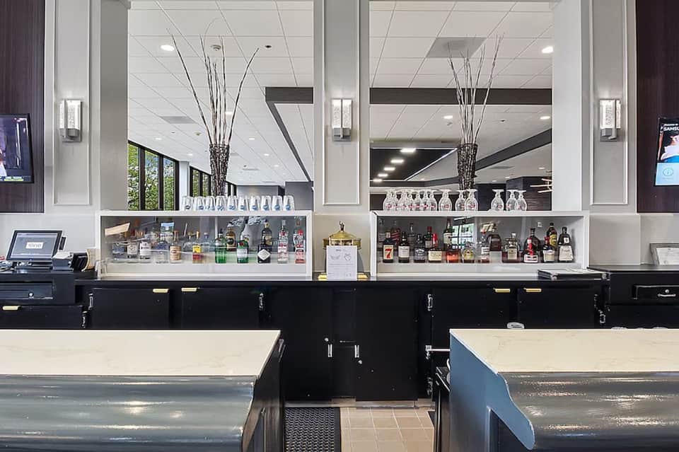 Hotel bar with mirrored shelving displaying liquor bottles and white ceiling details