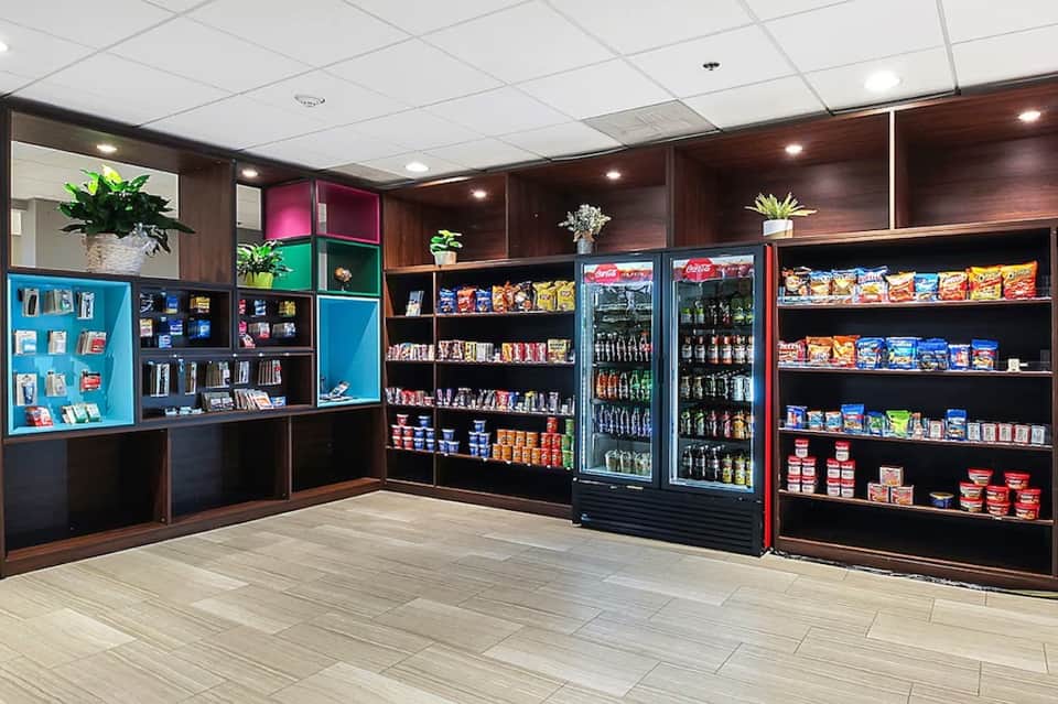 Hotel retail shop interior with wooden shelving, beverages, snacks, colorful product displays, and plants
