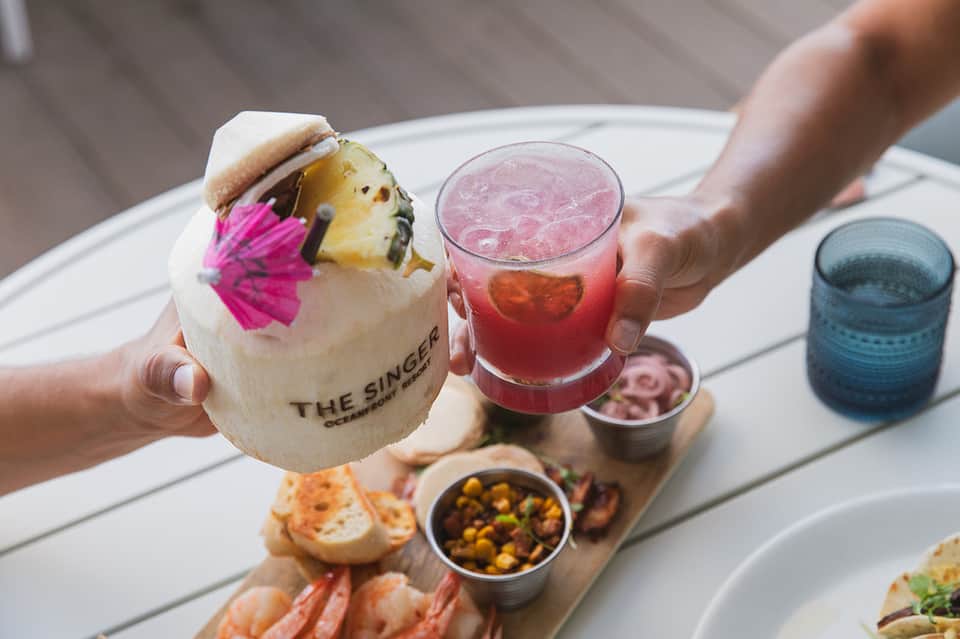 Tropical cocktail and pineapple burger with fresh sides and colorful garnishes at beachfront restaurant