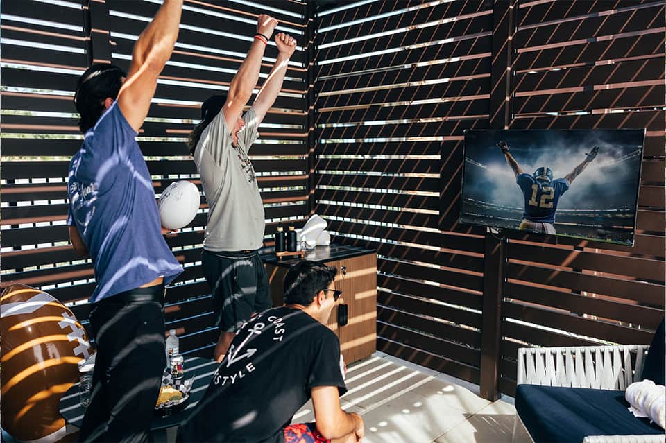 Recreation room with slatted wood walls, TV, and people celebrating