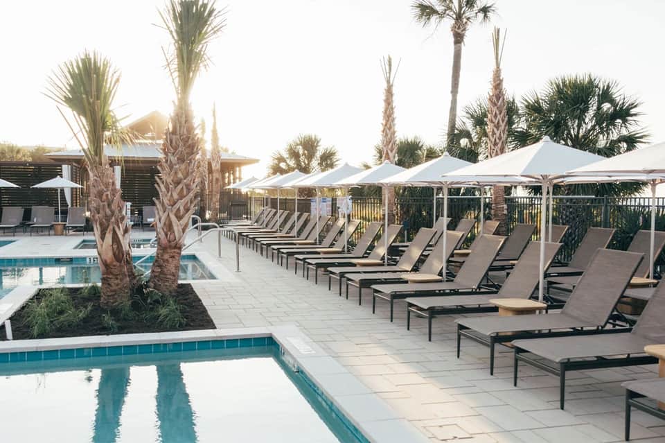 Resort pool deck with palm trees, loungers, umbrellas, and spa facilities