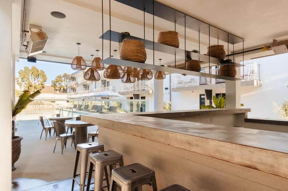 Modern resort bar and lounge with woven pendant lights, wooden counter, and ocean view