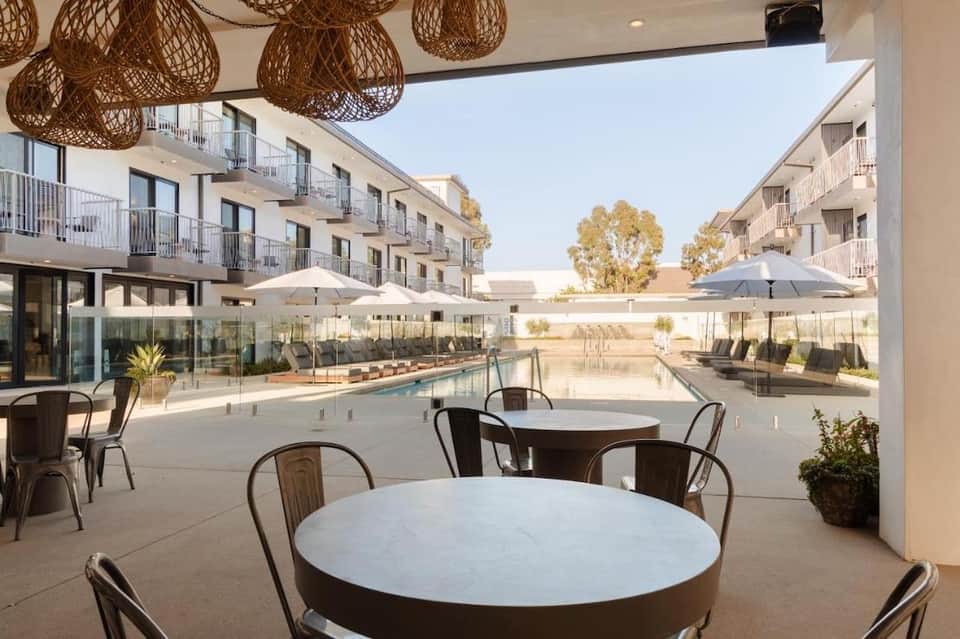 Poolside dining area with round white tables and modern apartment buildings in background