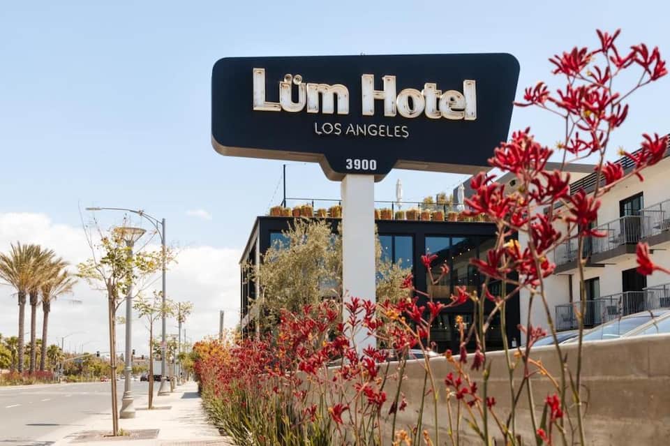 Lüm Hotel Los Angeles exterior signage with red flowers and palm trees on Wilshire Boulevard