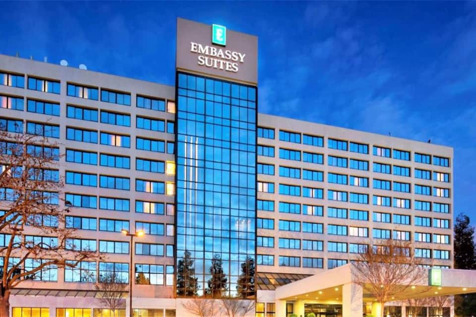 Modern Embassy Suites hotel building facade at dusk with illuminated windows