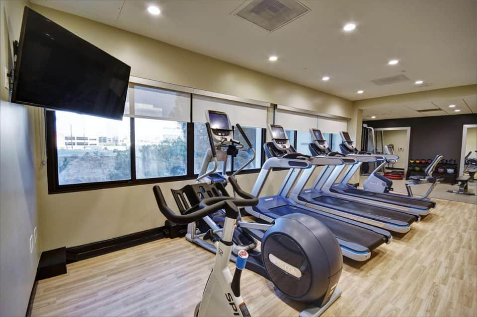 Indoor fitness center with treadmills and stationary bikes facing large windows with mountain views