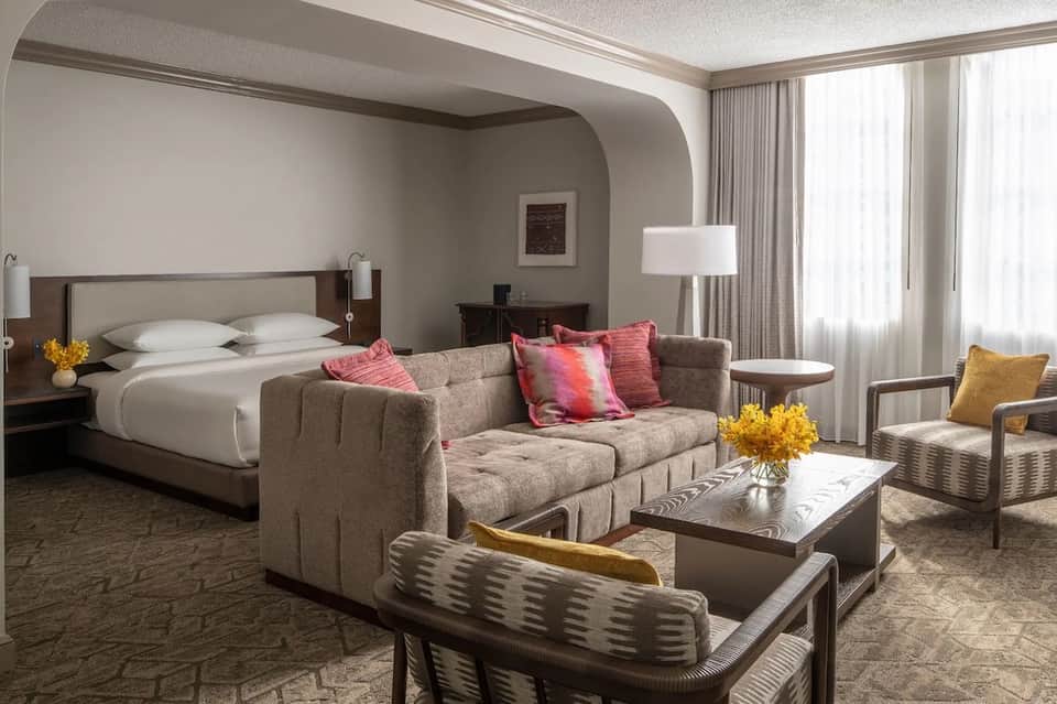 Luxury hotel suite with bed, gray sofa, colorful pillows, and modern furnishings