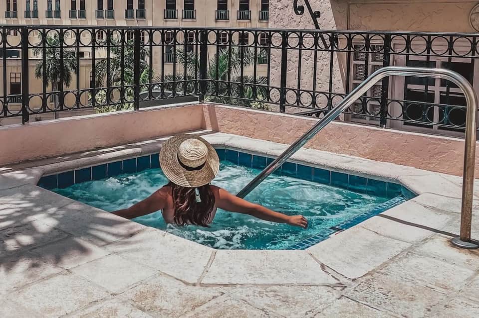 Person relaxing in small decorative pool with ornate black railing and historic building