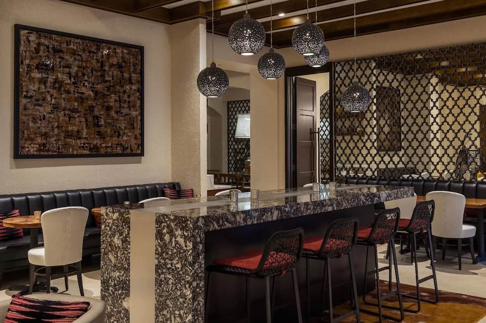 Modern lounge bar with black geometric pendant lights and marble-topped counter seating