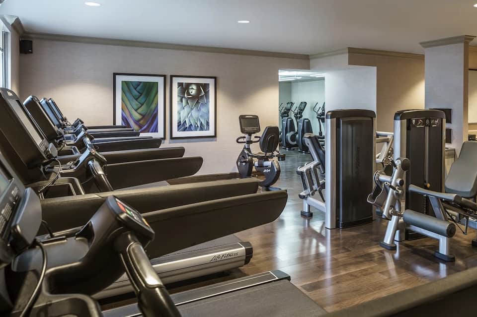 Modern fitness center with treadmills, cardio equipment, and framed abstract artwork on walls