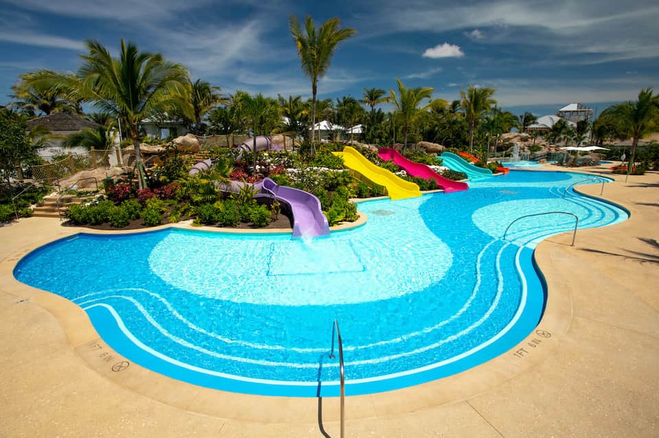 Resort water park with bright colored slides, winding lazy river, and palm trees