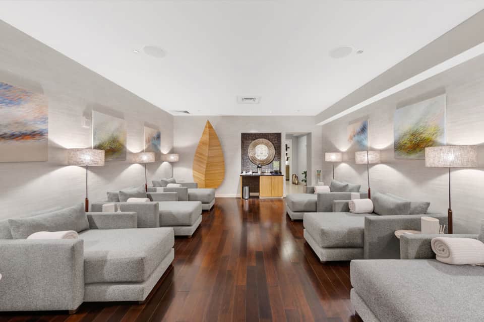 Spa relaxation lounge with gray modular seating, decorative artwork, wooden accents, and soft ambient lighting