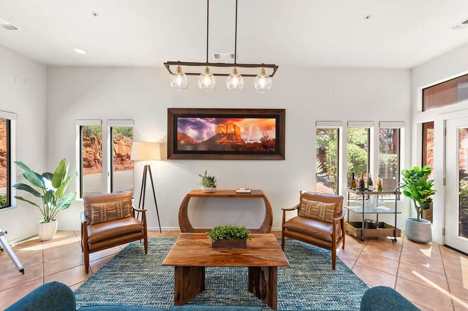 Modern living room with mid-century furniture, framed landscape art, and glass patio doors