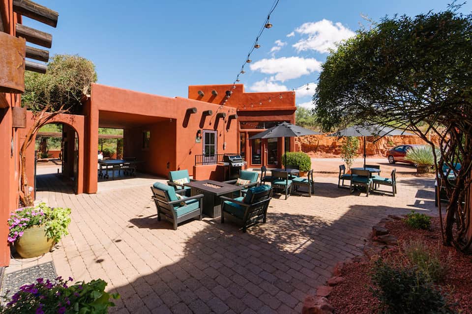 Red-orange courtyard with fire pit seating, covered patio, and desert landscaping