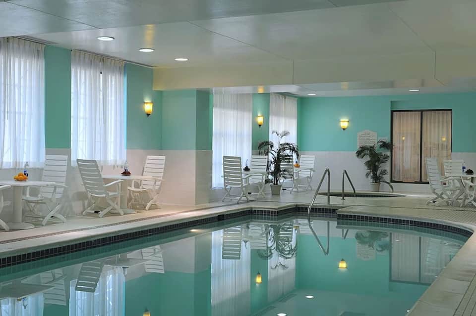 Indoor pool with turquoise water, white Adirondack chairs, mint green and white walls with natural lighting