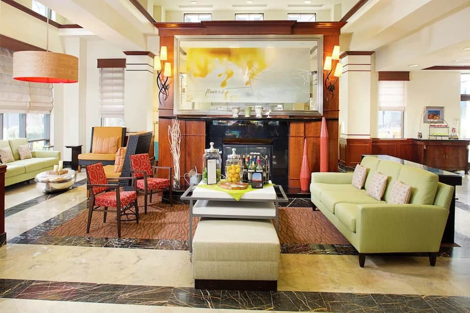 Upscale hotel lobby with lime green sofas, red accent chairs, fireplace, and modern decor